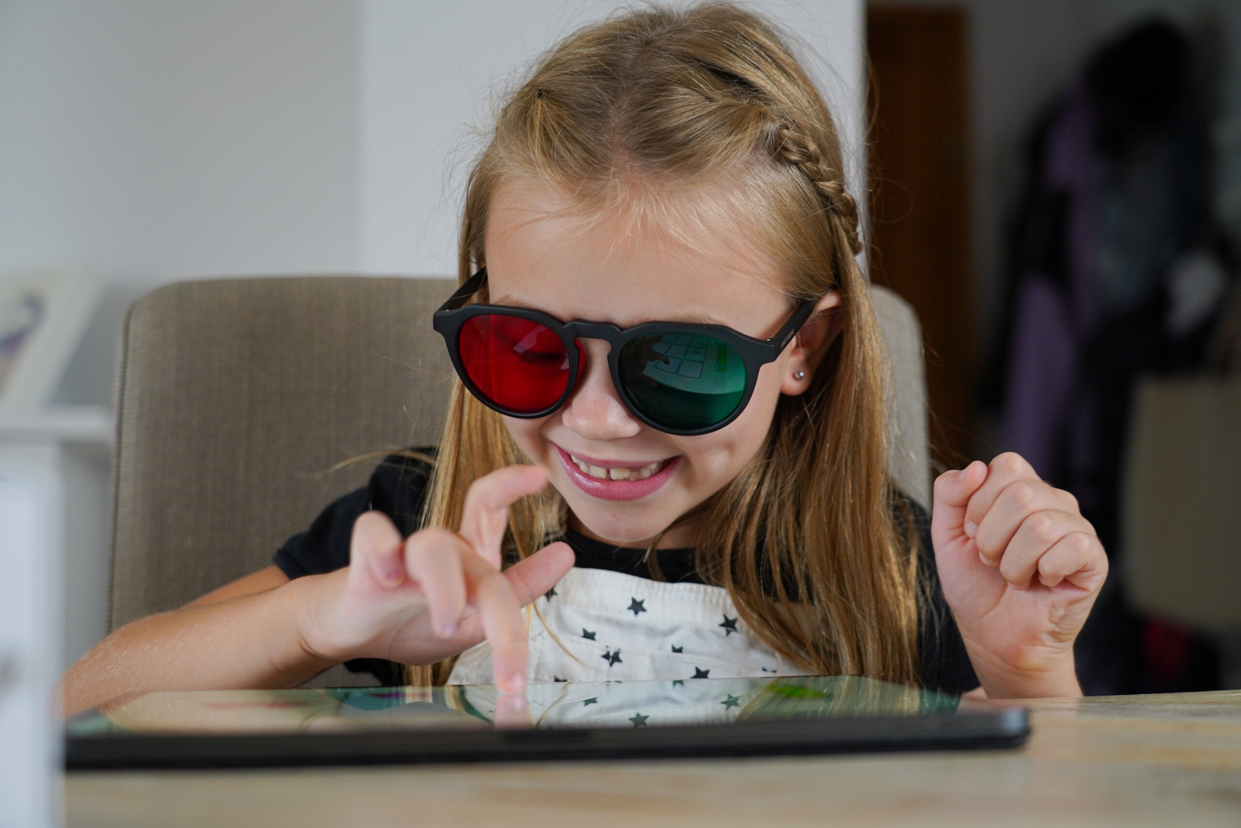 Meisje met rood-groene bril dat lachend traint met Eye Hero op een tablet